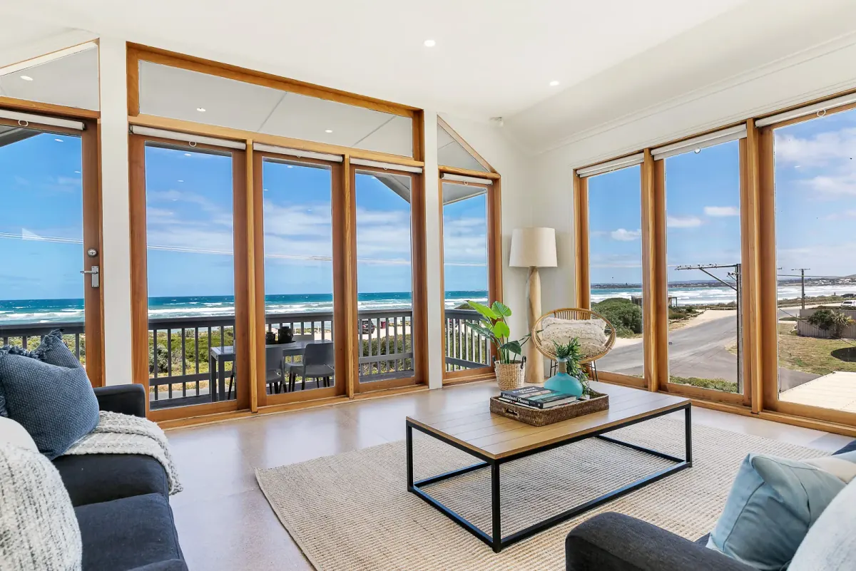 Living room with timber-framed windows opening onto a beach, shot on a real listing and edited in FotoPal Real Estate